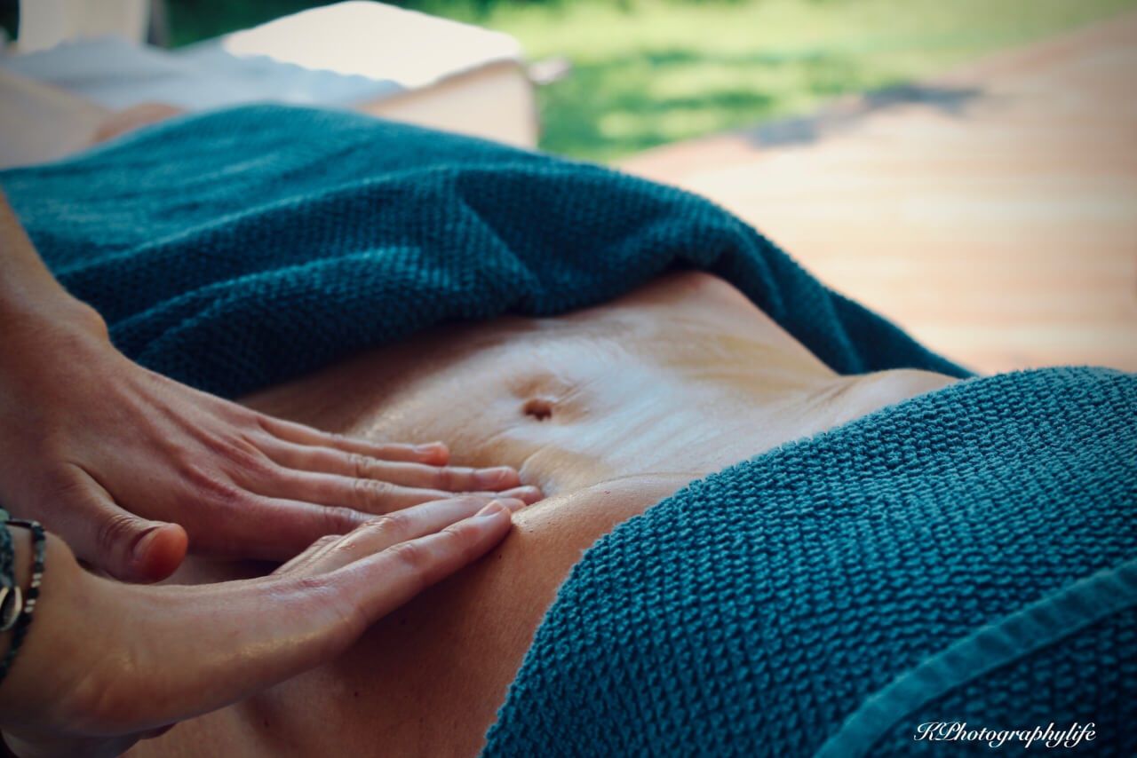 Deux mains qui massent le ventre d'une femme