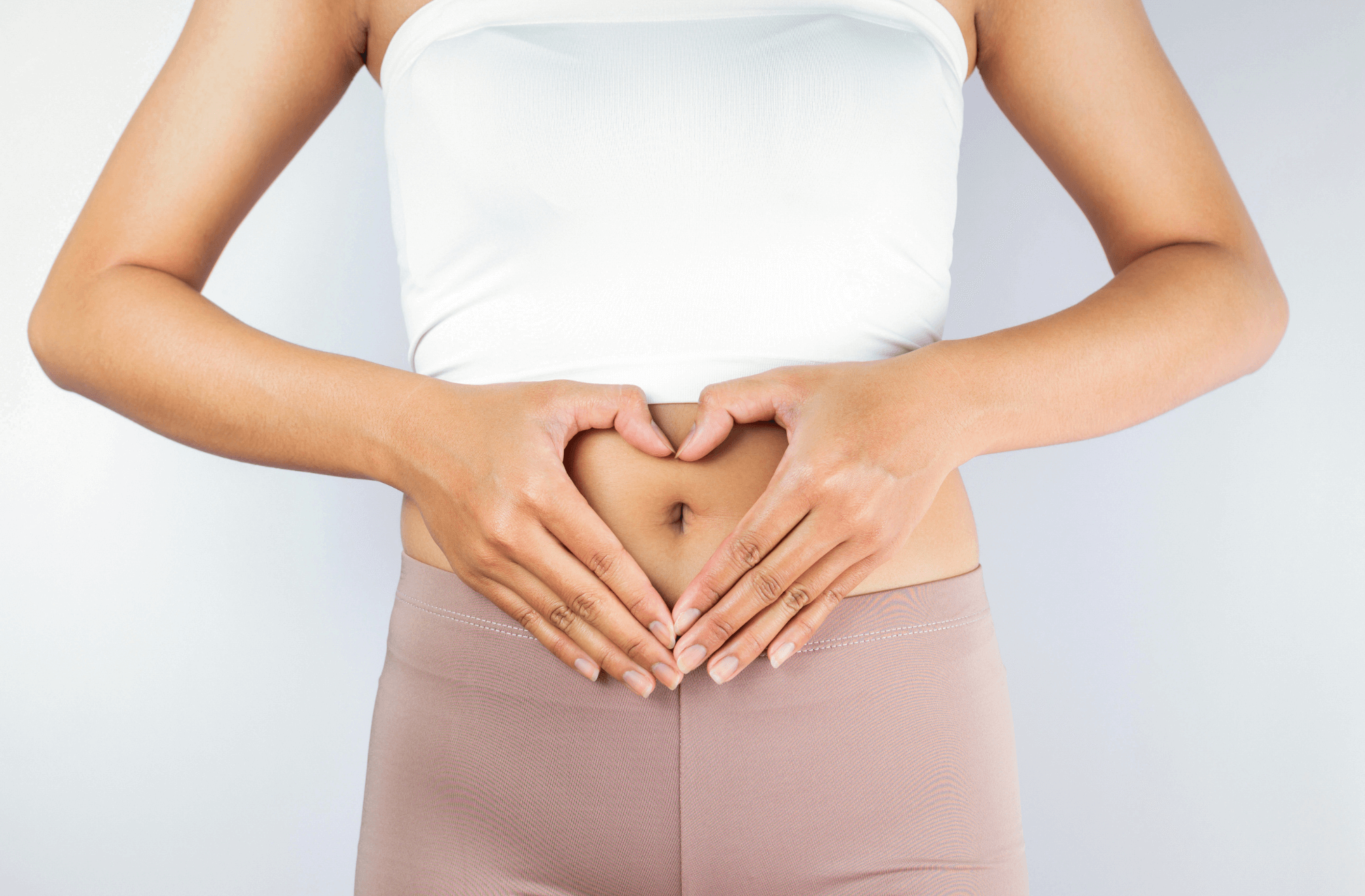 femme qui pose ses mains sur son ventre en formant un cœur