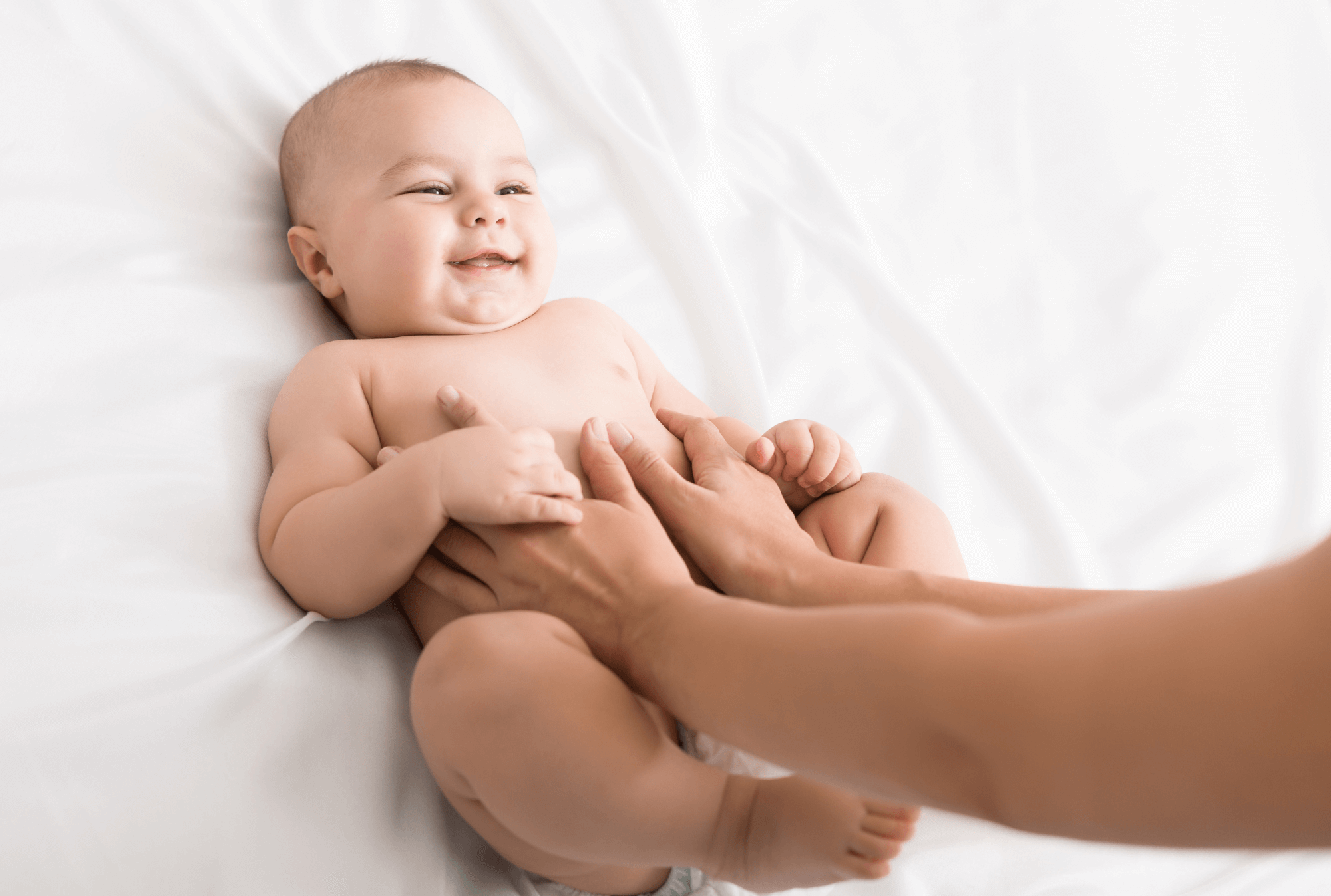 Un bébé souriant qui se fait masser le ventre