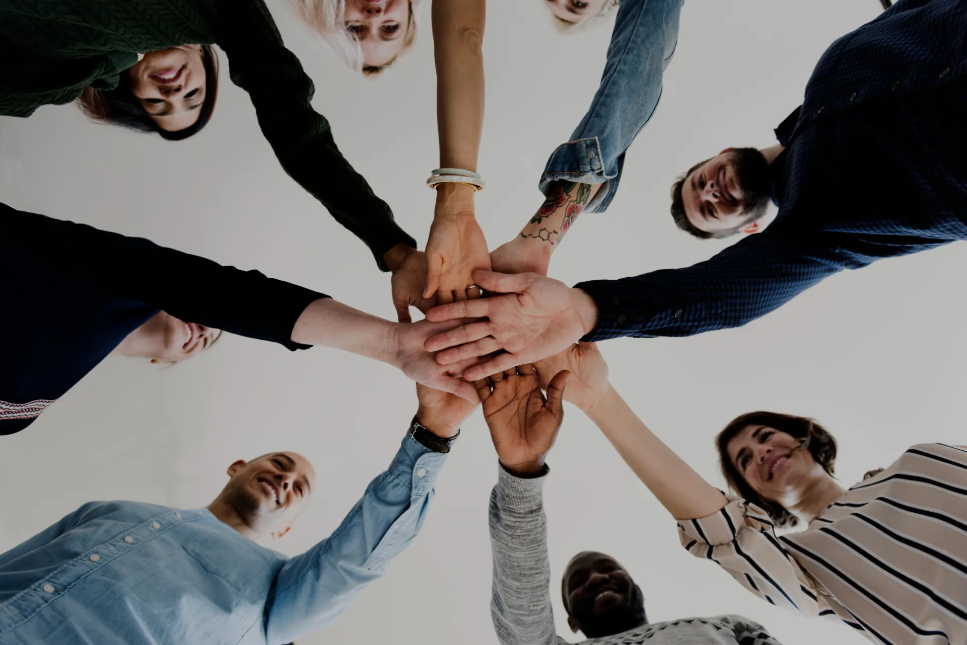 Team members joining hands in a circle symbolizing collaboration and unity within the WaveMed medical communications agency