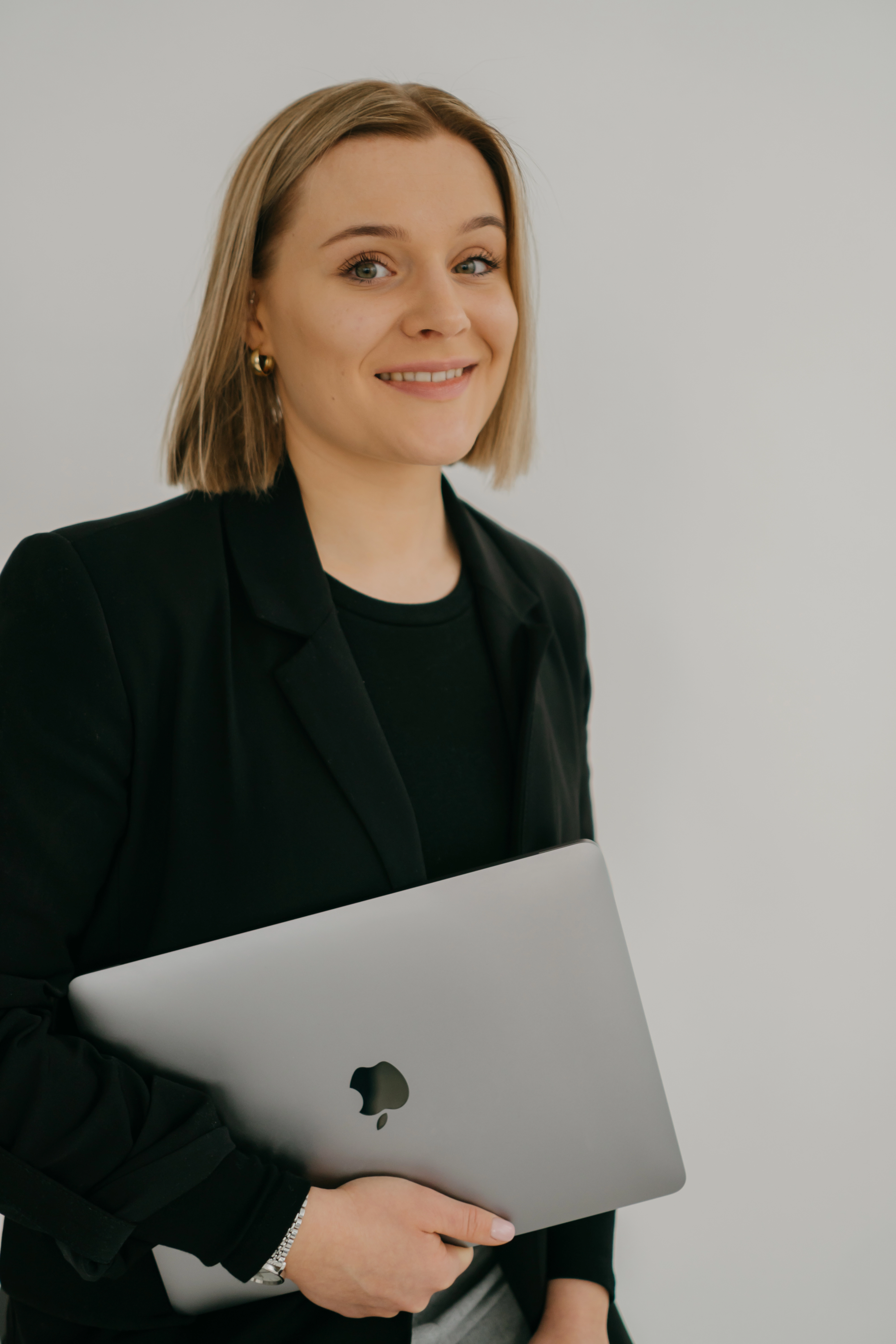 Founder of WaveMed agency holding a laptop and presenting a professional portrait in a neutral studio setting