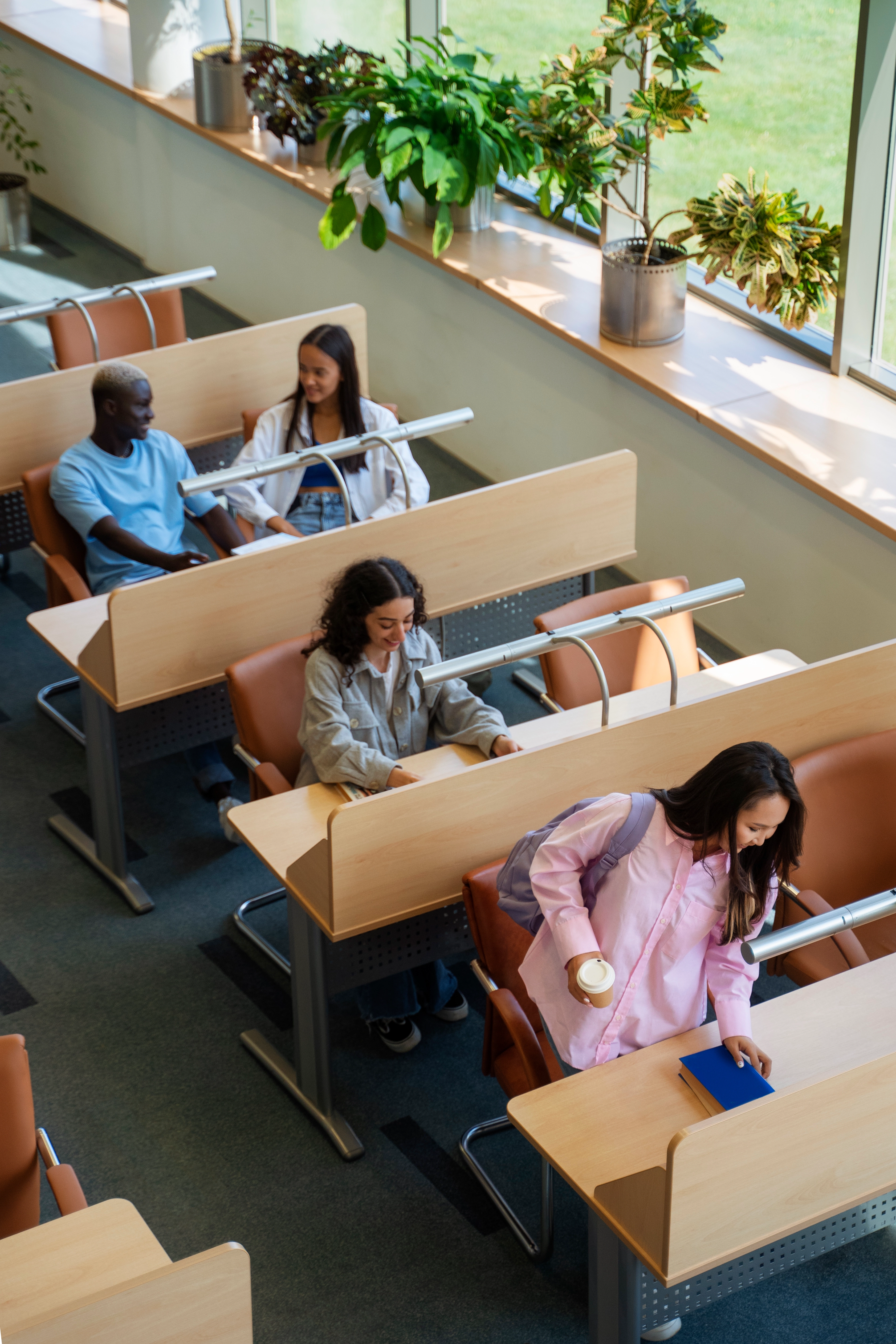 Students collaborating in a bright university library during an educational needs assessment, developed by WaveMed Medical Comms