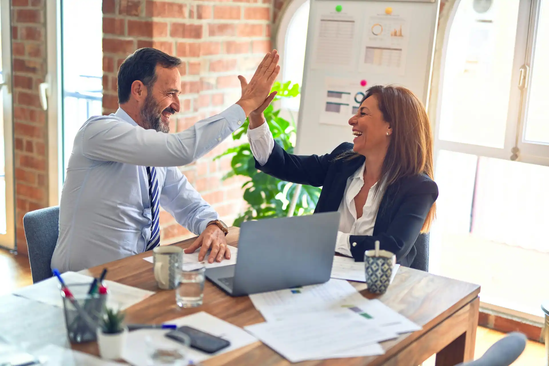 Two coworkers give a high five while discussing medical marketing presentations for medical and sales reps