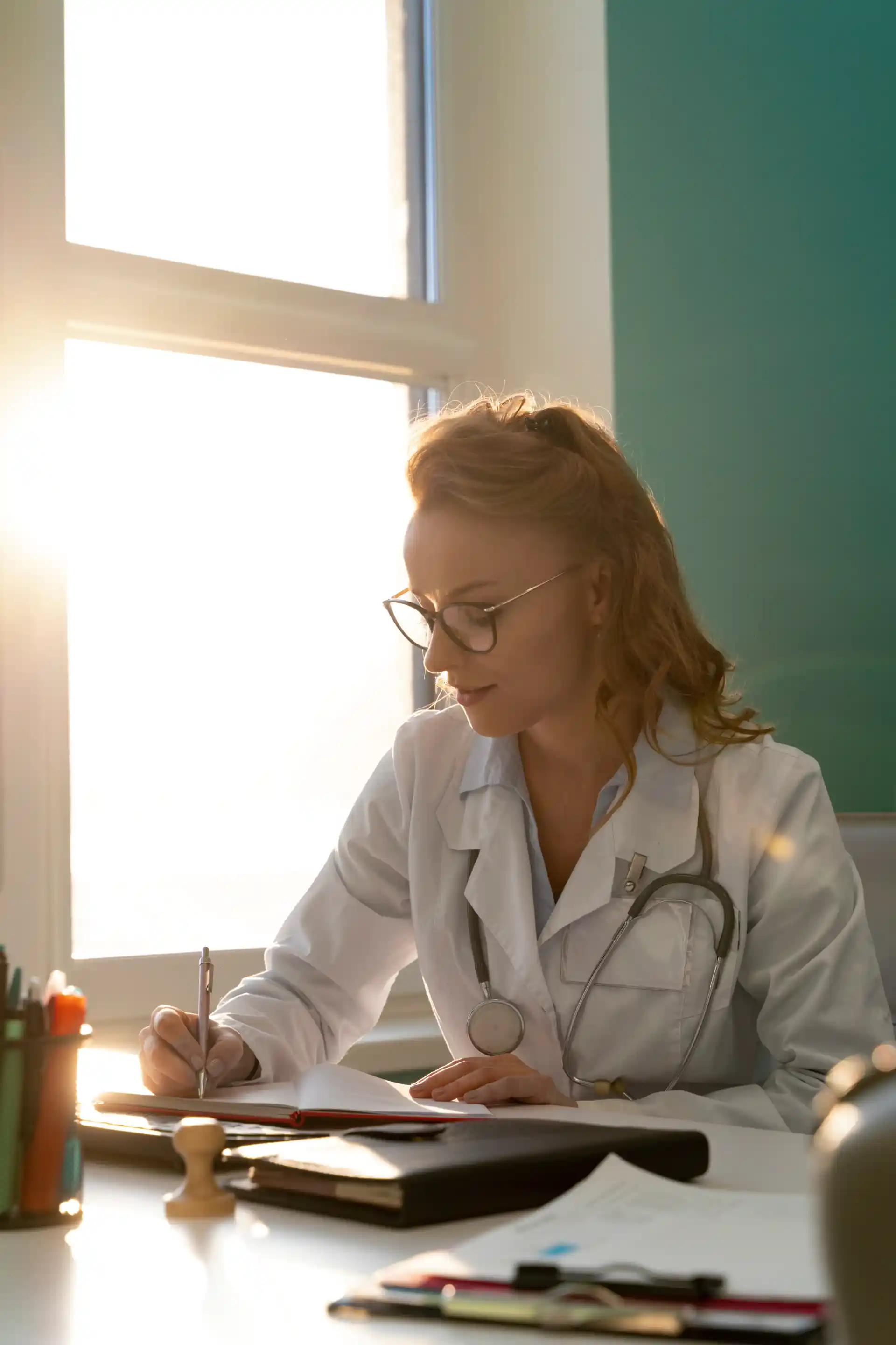Doctor writing notes at a desk in sunlight symbolizing the medical writing process and creation of scientific content