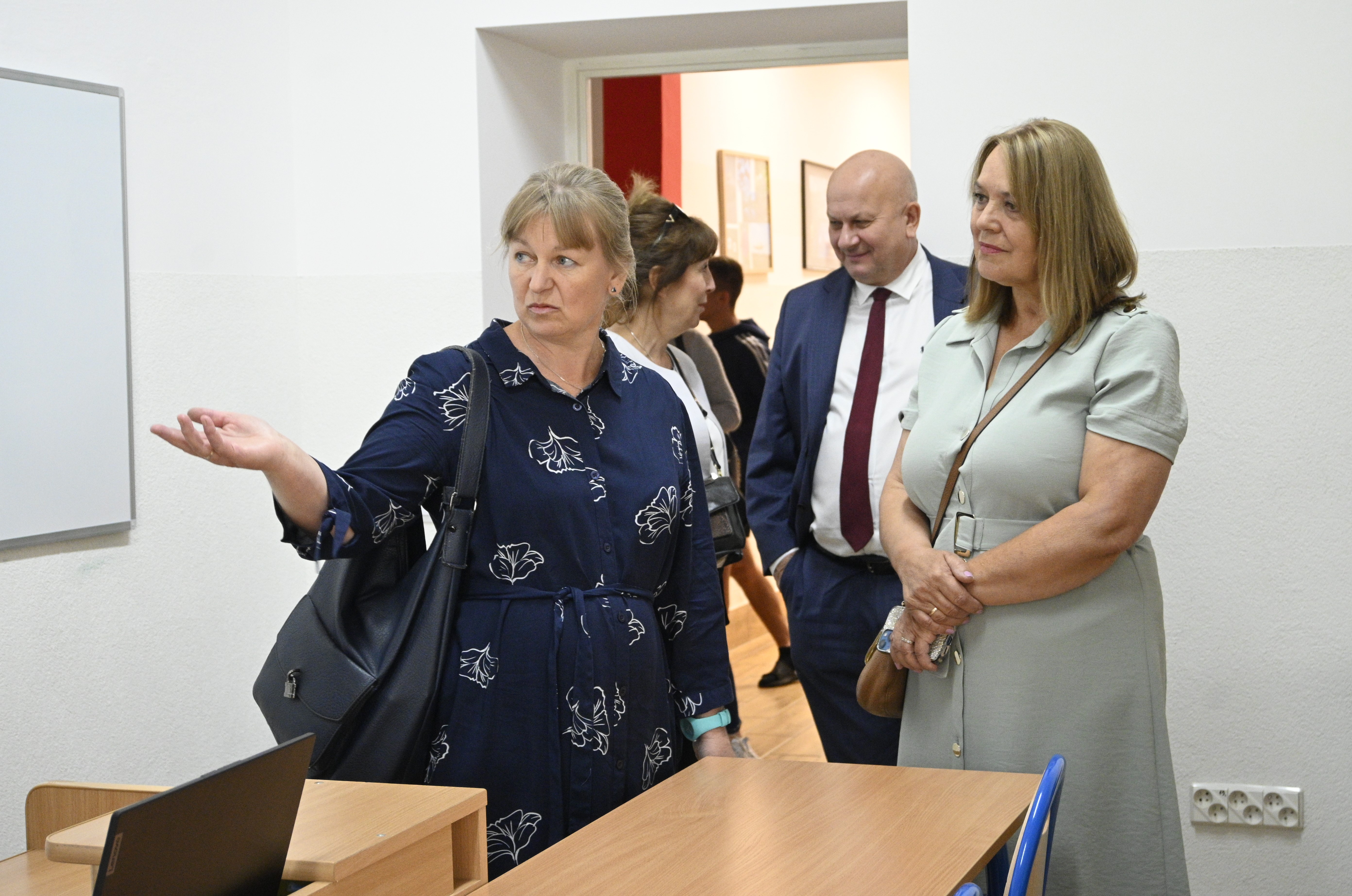 Uroczyste podsumowanie projektu „Dostępna Szkoła” | Pani Poseł T. Pamuła oraz Starosta lubaczowski Pan Z. Swatek oprowadzani przez pracownika MOW oglądają jedną z sal lekcyjnych.  Z przodu fragment ławki i biurka z laptopem, na ścianie tablica..JPG