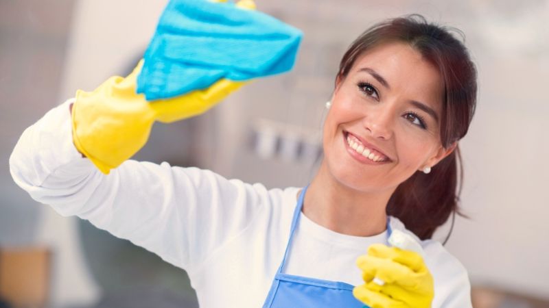 Een huishoudelijke hulp maakt schoon et een doek