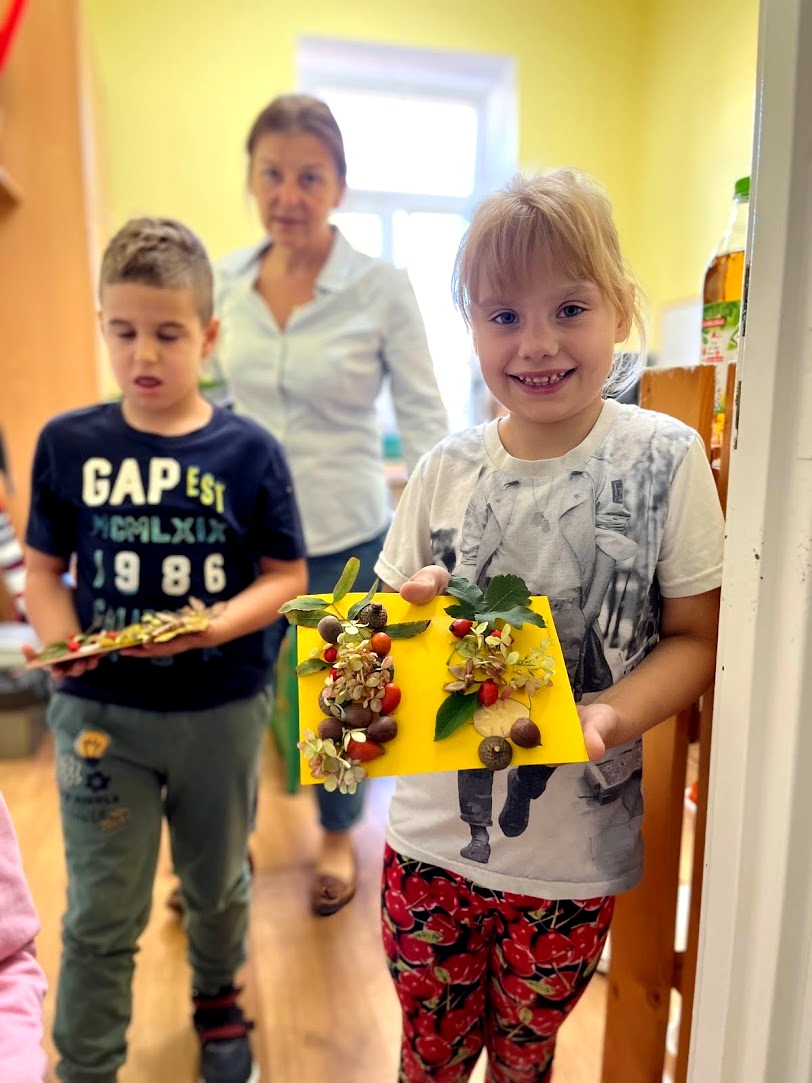 Powitanie Jesieni | Dziewczynka i chłopiec wychodzą z sali pokazując swoje prace.jpg