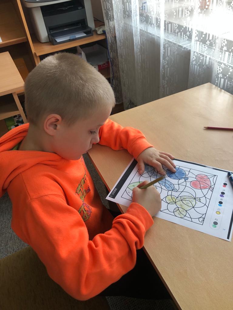 Pozalekcyjne zajęcia w bibliotece | Chłopiecz przy stoliku koloruje obrazek.jpg