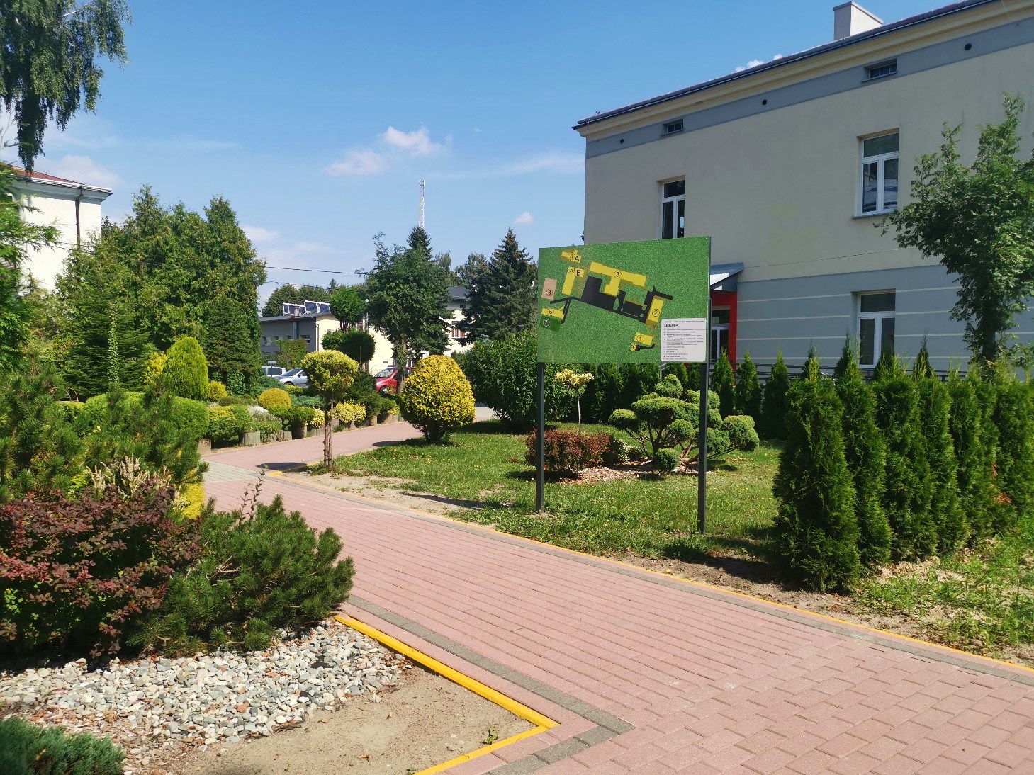 „Przyjazna przystań” | czerwony chodnik z żółtym krawężnikiem, dookoła rośliny i drzewa.jpg