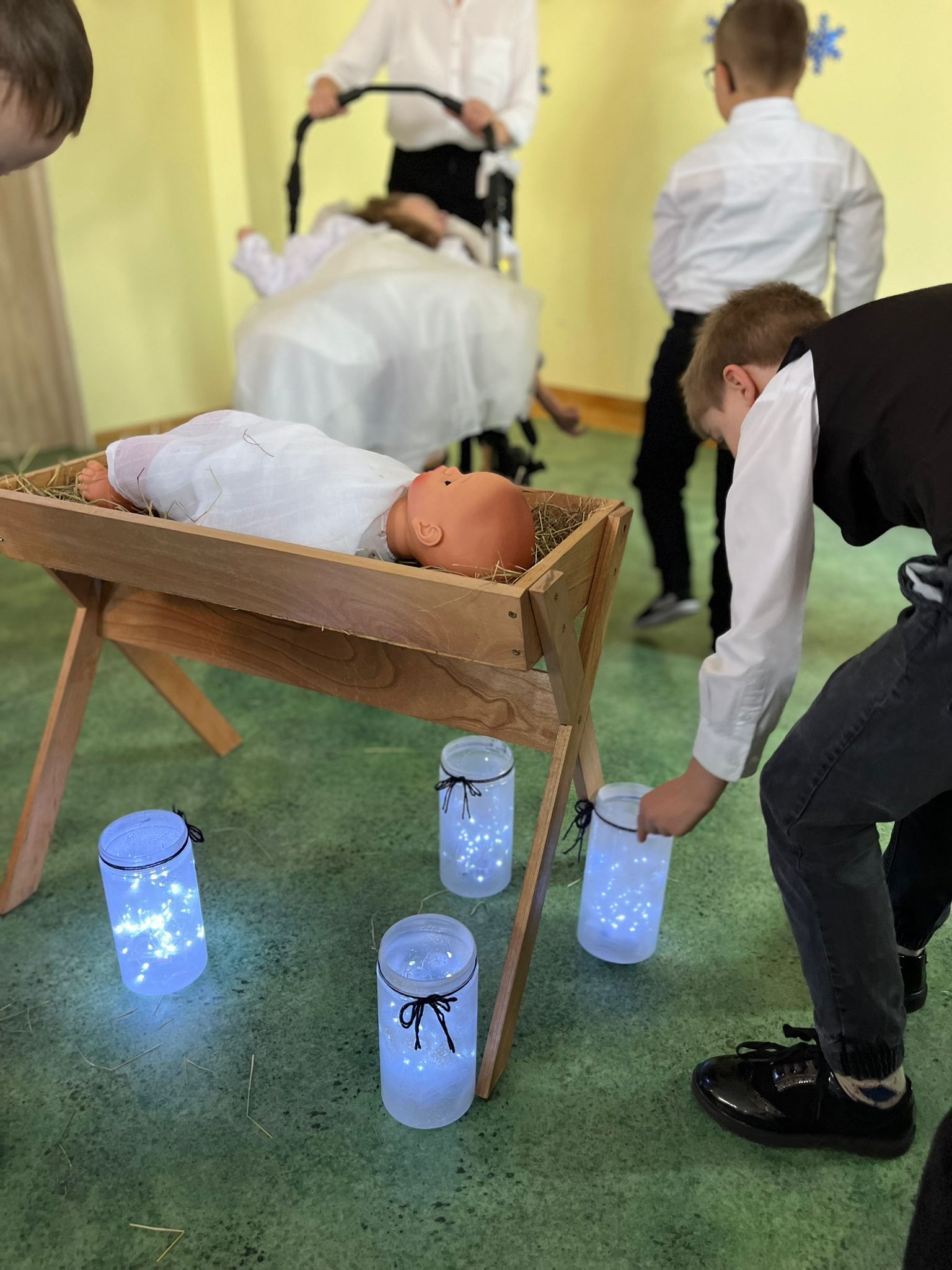 Taniec NOEL | Chłopiec stawia lampion na ziemi koło kołyski.jpg
