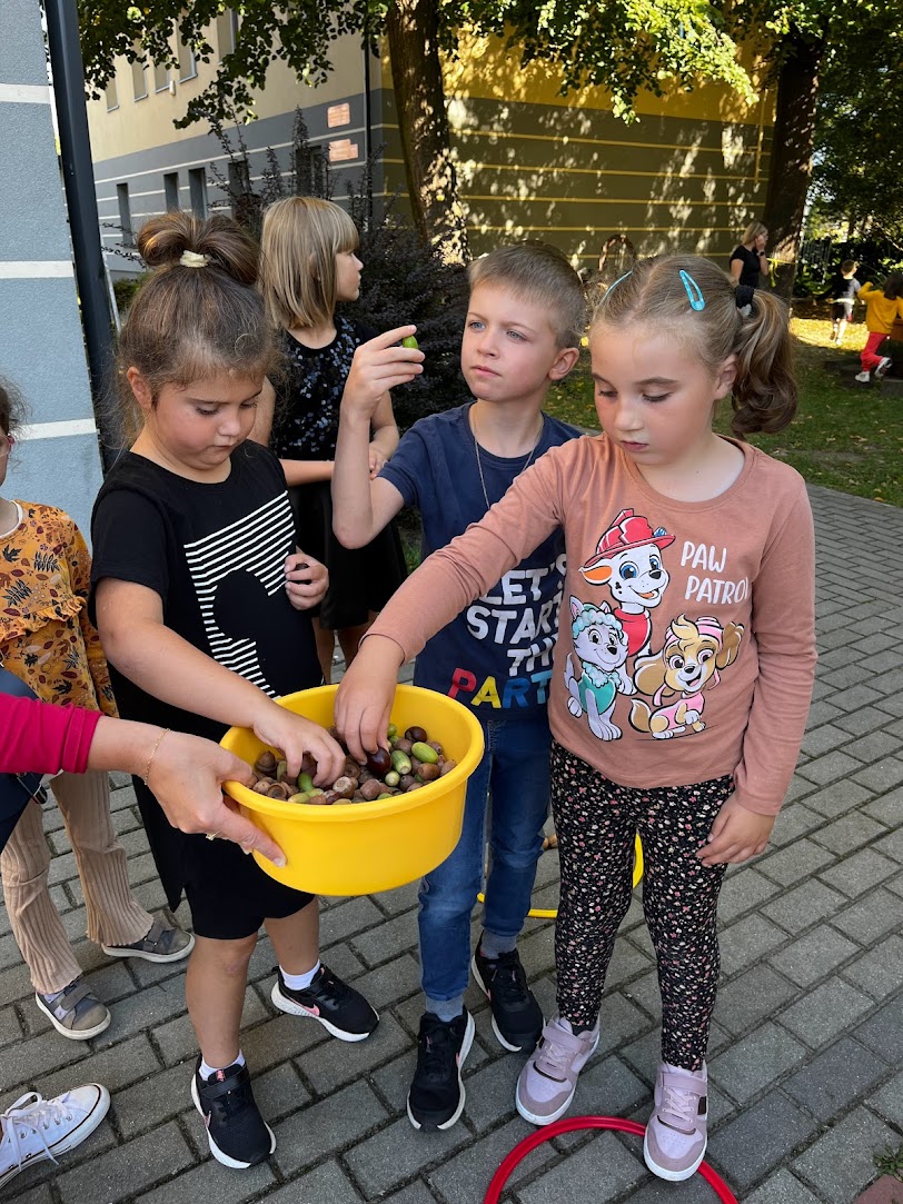 Powitanie Jesieni | Dwie dziewczynki i chłopiec dotykaja i oglądają kasztany .jpg
