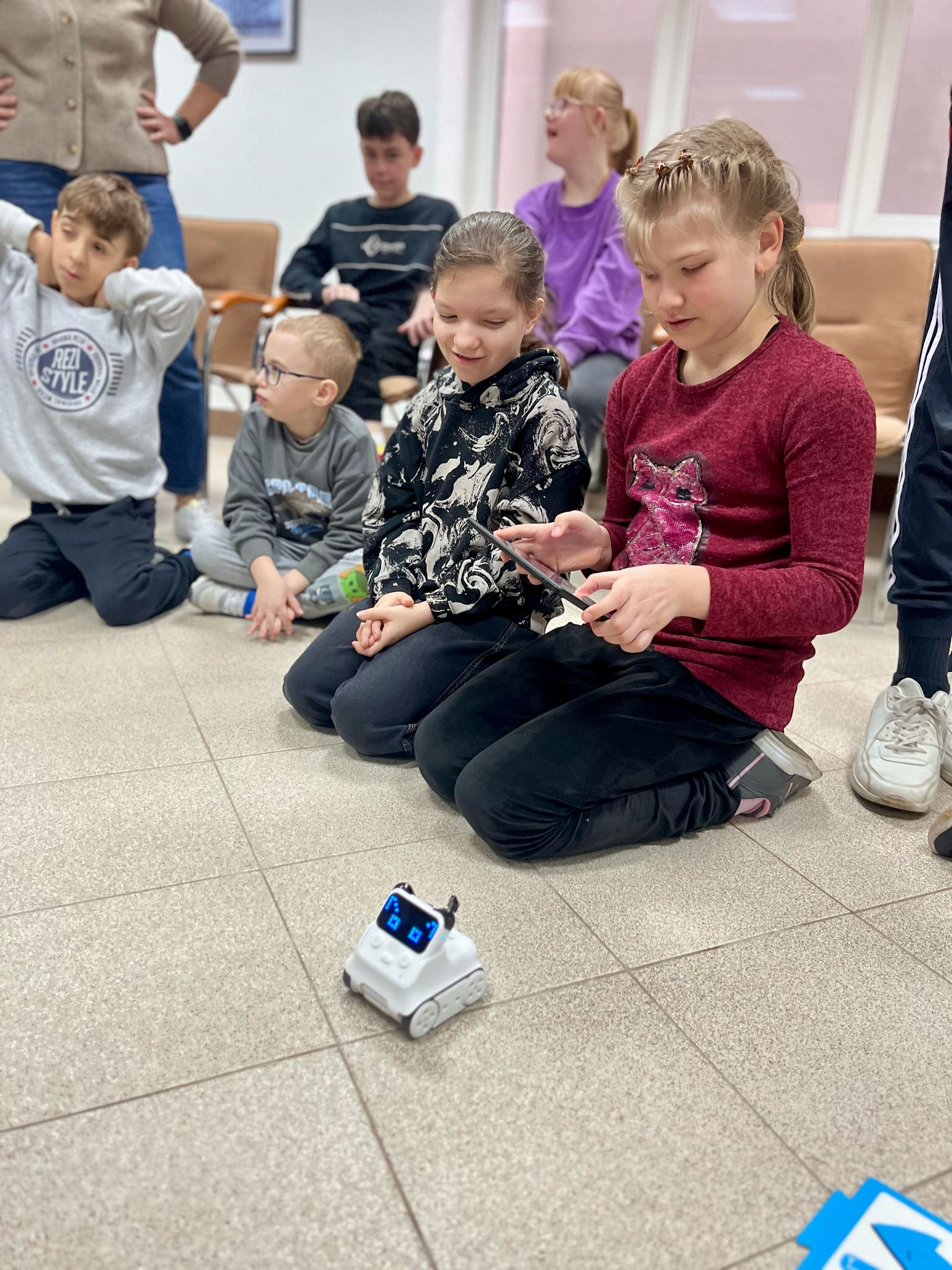 ROBOTYKA | Dzieci siedzą na podlodze, jedna dziewczynka steruje tabletem robota.jpg