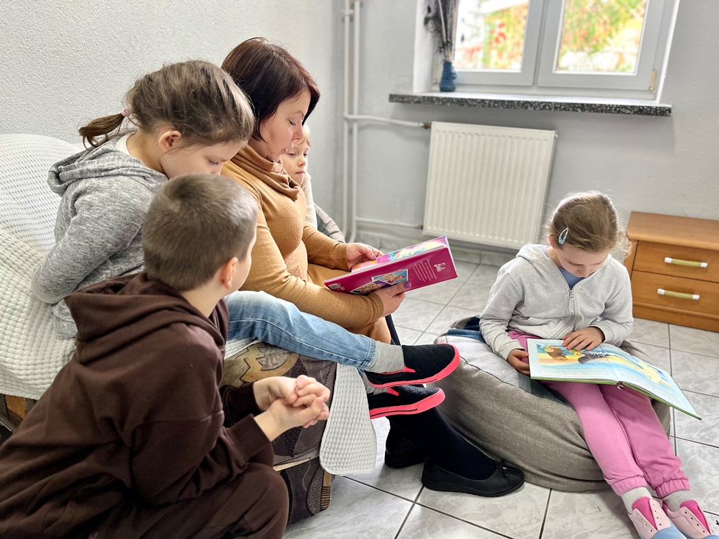 Zrób sobie przerwę na czytanie | nauczyciej siedzi na fotelu i czyta dzieciom bajki.jpg