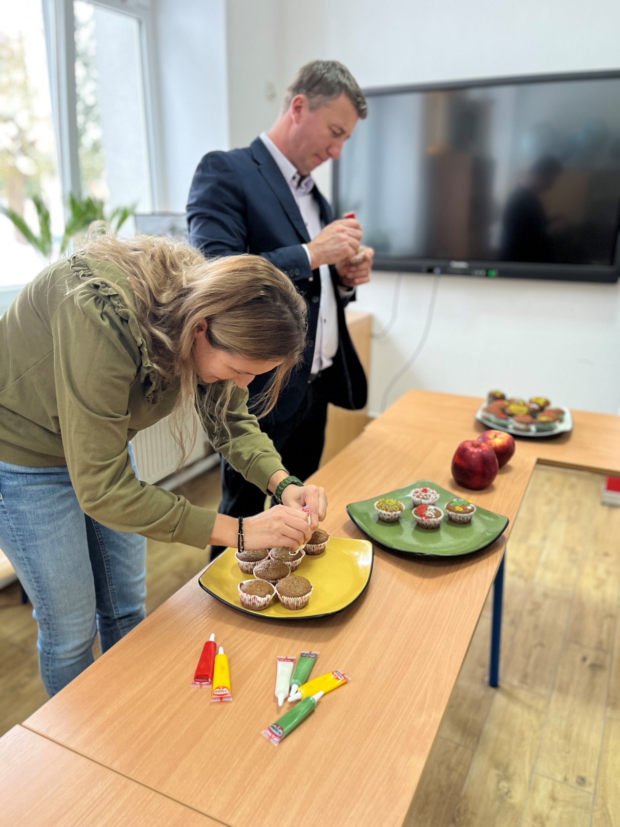 Przedświąteczne warsztaty kulinarne | Kobieta i mężczyzna dekorują Muffinki.JPG