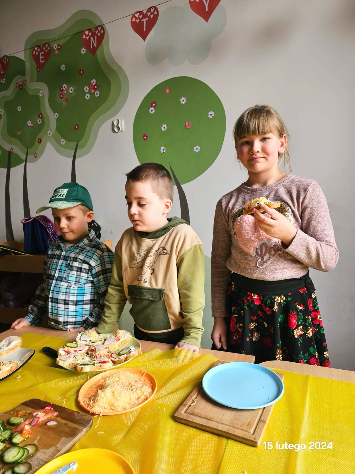 Dzień Babci i Dziadka w przedszkolu | dzieci przy stoliku jedzą kanapki.jpg