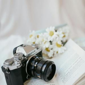 A camera and book on a bed with daisies