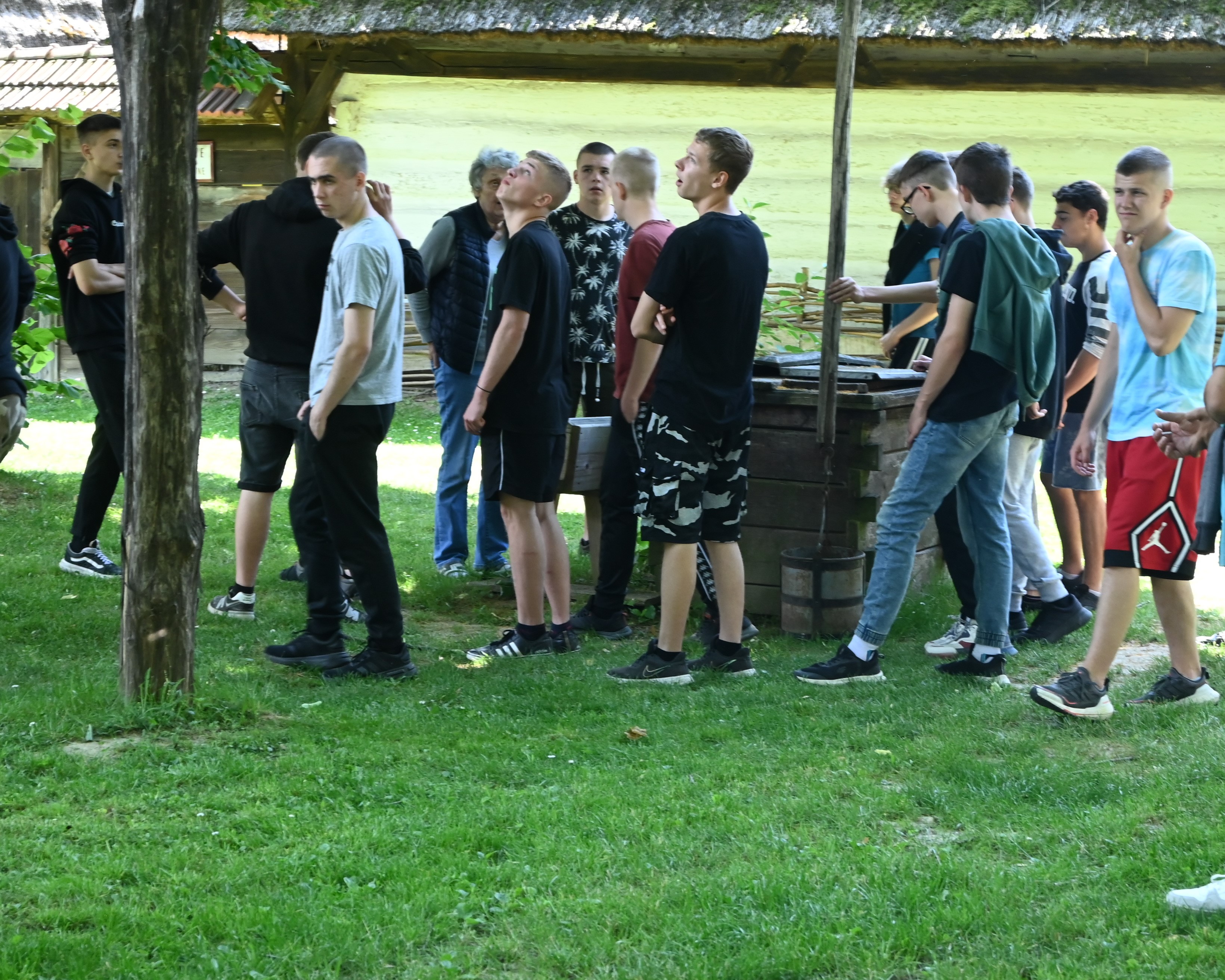 Wycieczka do Markowej | Grupa chłopców stoi na trawie wokół cembrowiny studni z żurawiem..JPG