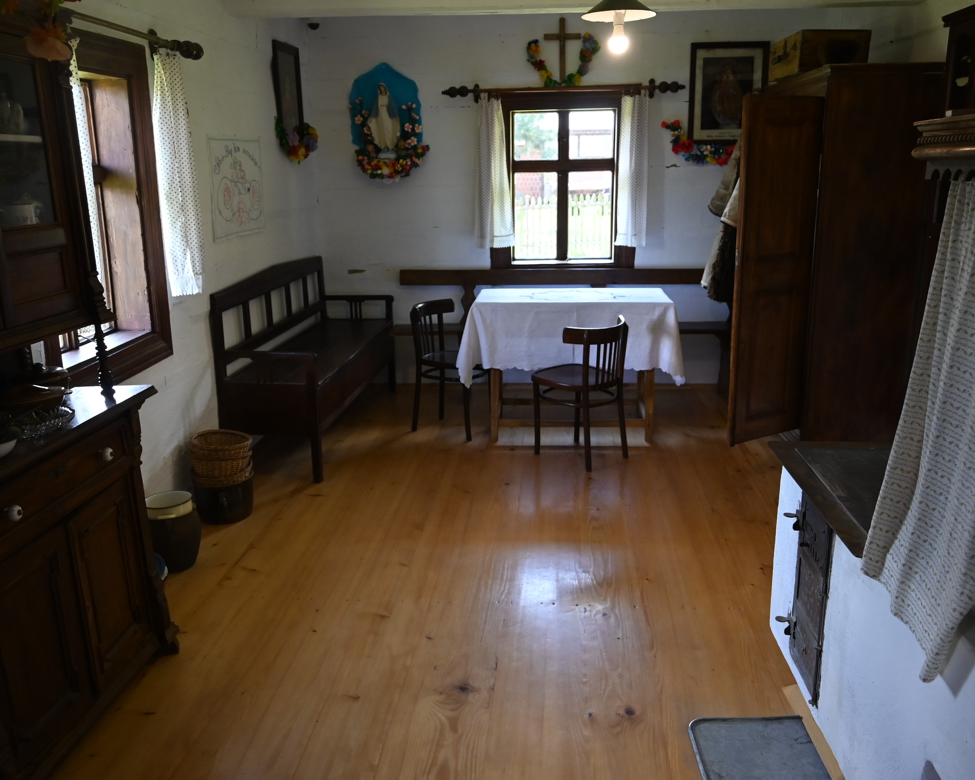 Wycieczka do Markowej | Wnętrze izby starego domu. Podłoga z desek, pod oknem stół i krzesło, obok ława, w rogu szafa. Widoczny fragment pieca z płytą do gotowania..JPG
