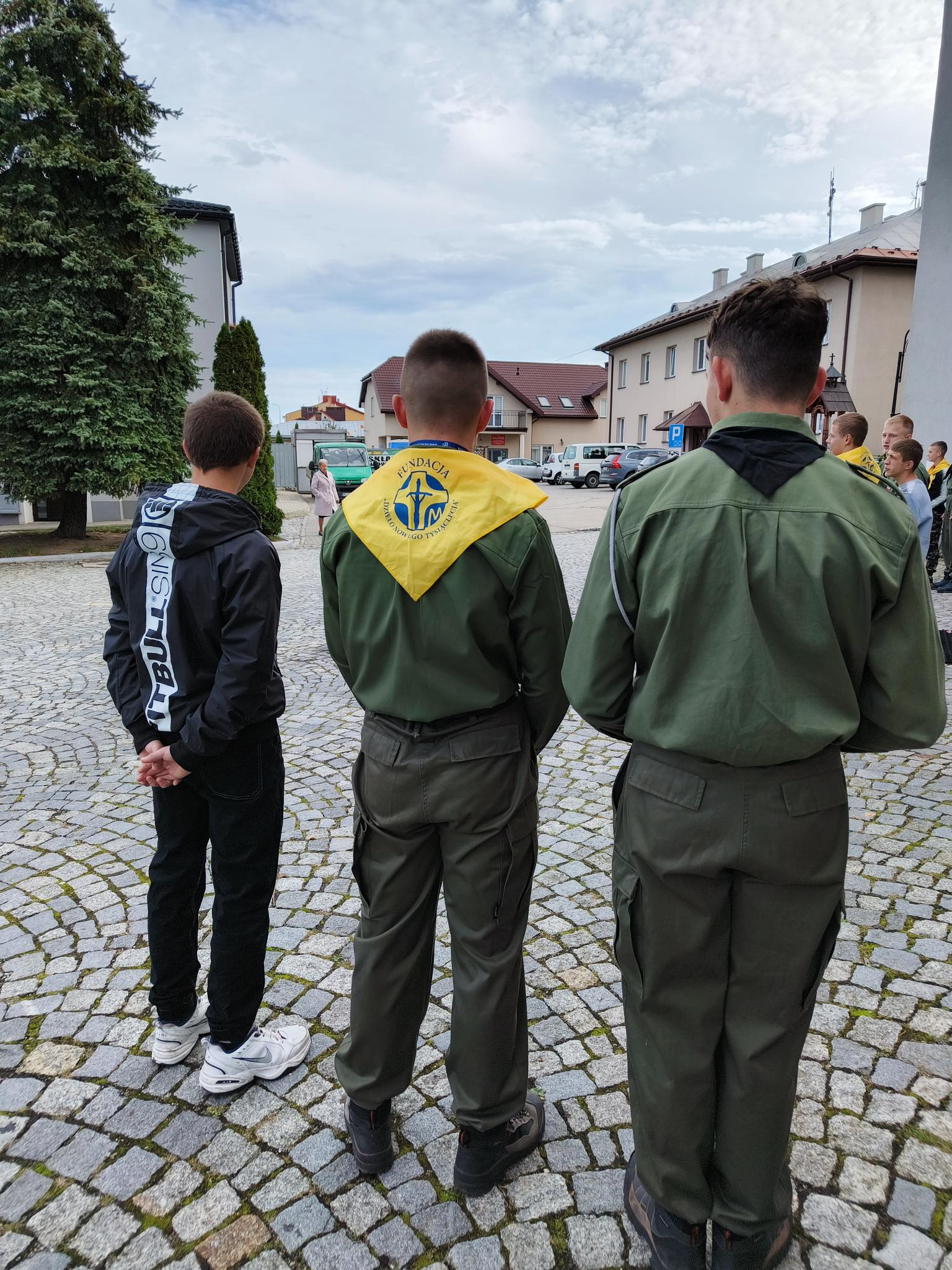 XXIV Dzień Papieski  | Dwaj wychowankowie w mundurach harcerskich, sojąc tyłem do obiektywu na chodniku przed kościaołem kwestują z  puszkiami akcji Dzieło Nowego Tysiąclecia..jpg