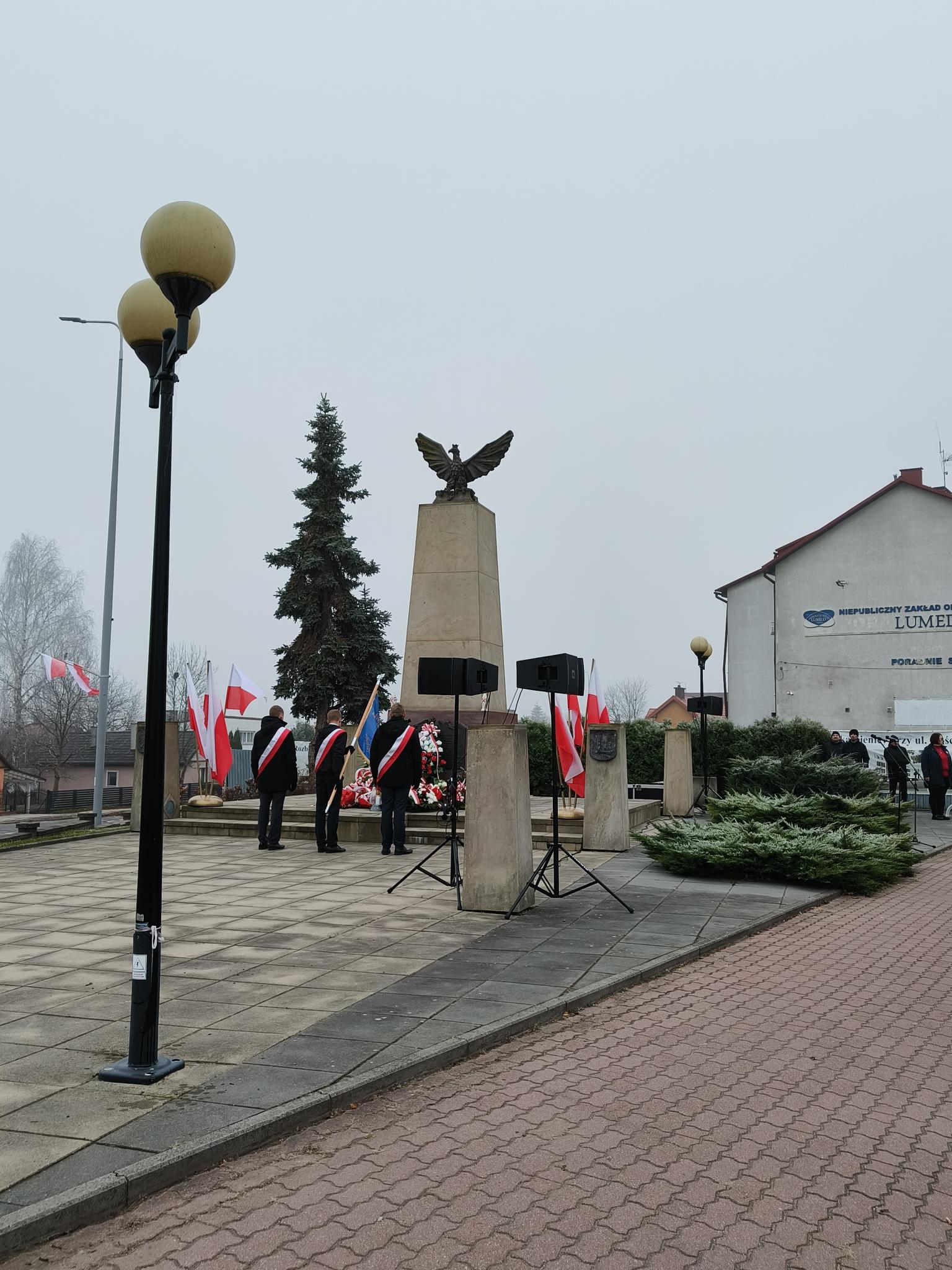 Obchody Święta Niepodległości | W centrum Pomnik Niepodległości, przed którym stoi poczet sztandarowy naszej placówki. Chorąży pochyla sztandar, asystujący stoją na baczność_.jpg