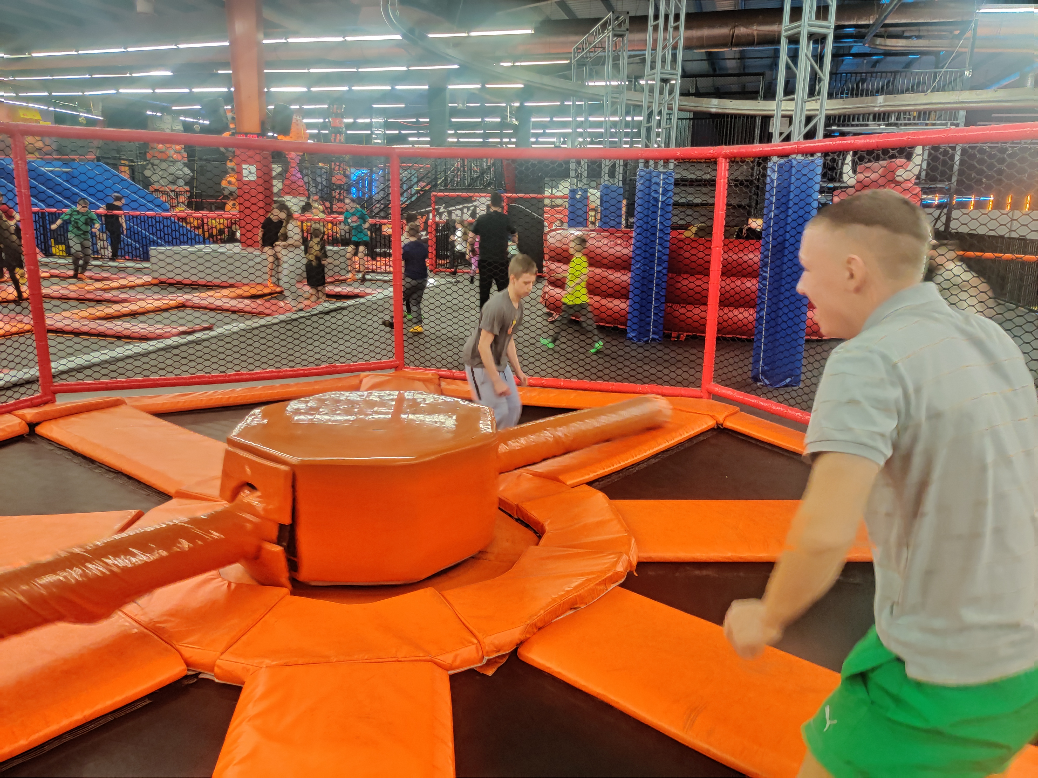 FLY Park  | W ogrodzonej siatkami przestrzeni z kołem i dwoma obrotowymi drążkami do przesakiwania stoją dwaj wychowankowie i czekają na zbliżającą się przeszkodę, którą muszą przeskoczyć. Są uśmiechnięci..jpg