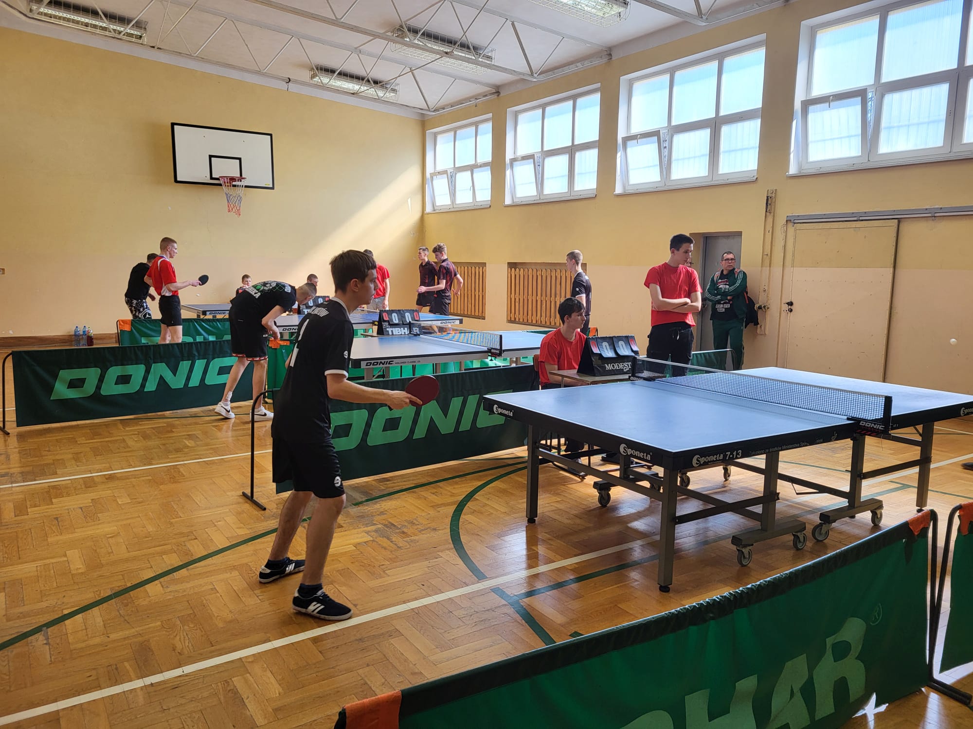 Turniej Eliminacyjny XXXIX Mistrzostw Polski MOW w Tenisie Stołowym  | W sali gimnastycznej widoczne są cztery stoły do tenisa przy których grają zawodnicy. Nasz wychowanek gra przy najbliżej zlokalizowanym stole..jpg