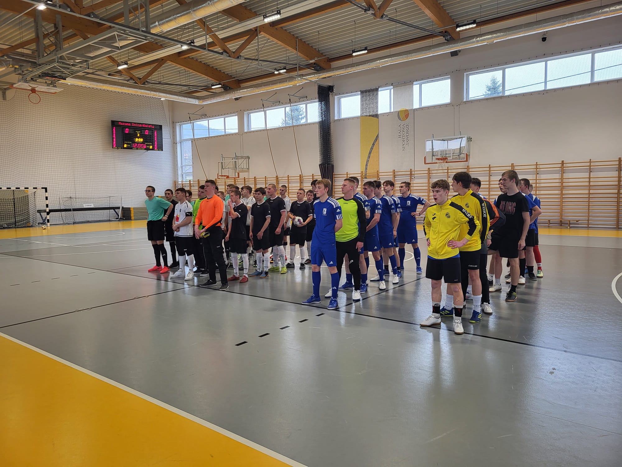 Turniej Eliminacyjny Mistrzostw Polski w Halowej Piłce Nożnej  | W hali sportowej pięć drużyn sportowych stoi ustawionych w rzędach, jeden za drugim. Nasza drużyna w środku, jako trzecia. Zdjęcie wykonane  z rogi sali..jpg