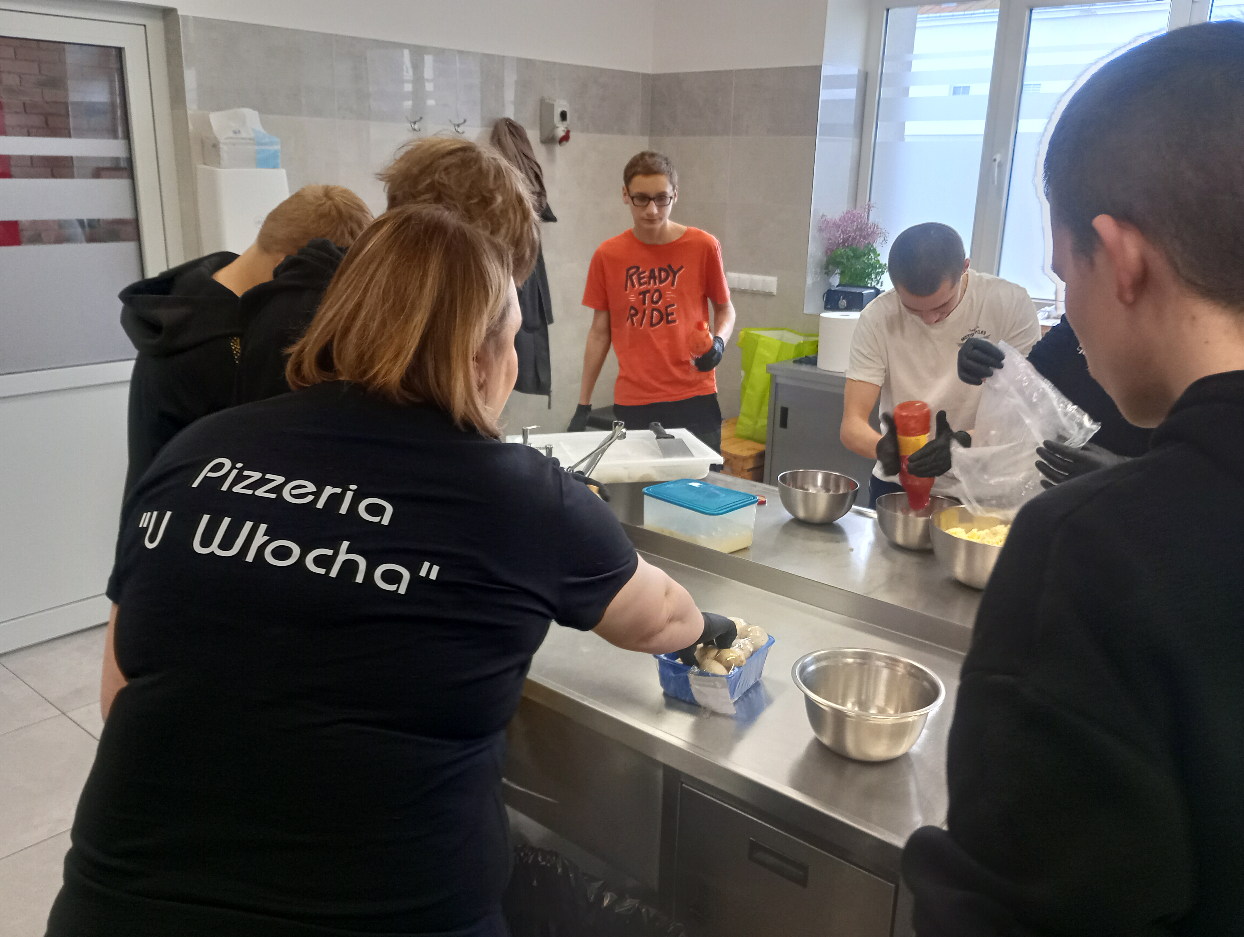 Spotkanie z pracodawcą w ramach Projektu Kariera bez Barier | W pracowni gastronomicznej wychowankowie prygotowują calzoni. Tyłem w T-shircie z nazwą Pizzeria u Włocha prowadząca wraz z wychowankami przygotowują produkty..jpg