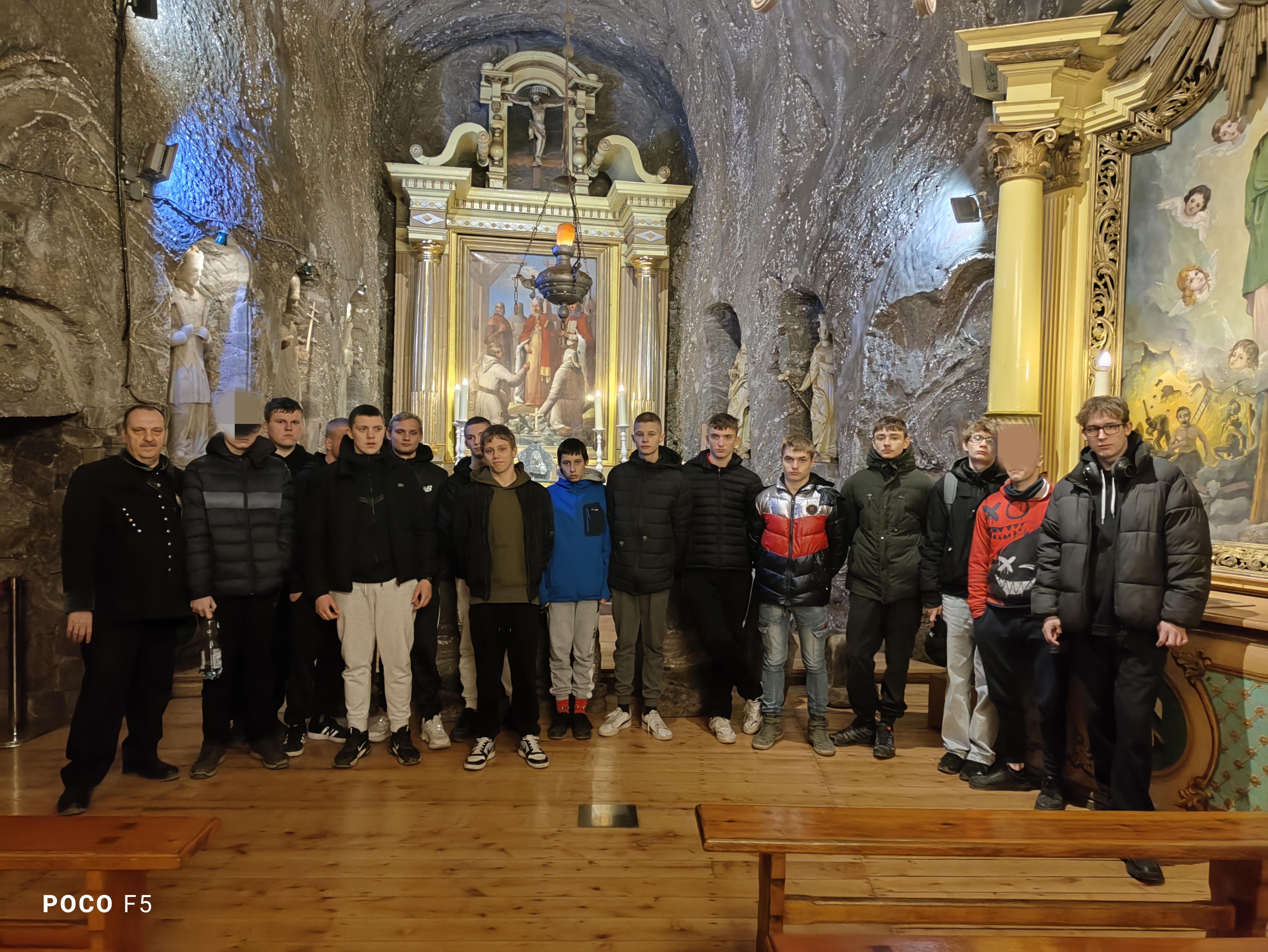 Wycieczka do kopalni soli  | Grupa wychowanków wraz z przewodnikiem w stroju górnika stoją w podziemnej komnacie, w której znajduja się umieszczone w ołtarzach obrazy sakralne..jpg