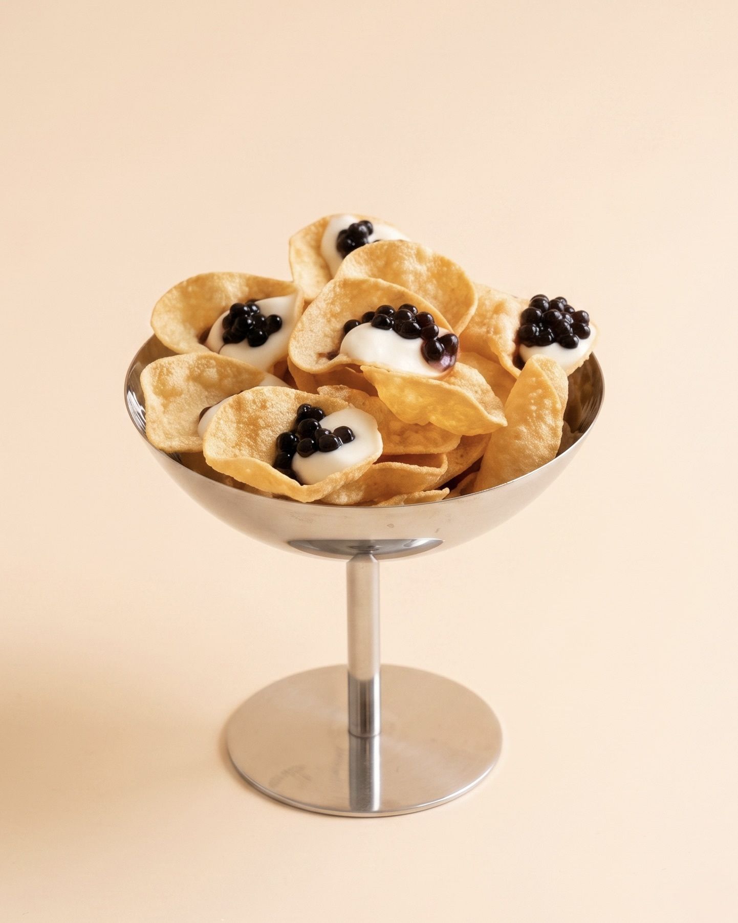 Linsenchips-Appetizer mit Yuzu-Mayonnaise und Essig-Perlen in einer modernen silbernen Schale auf hellem, beigen Hintergrund