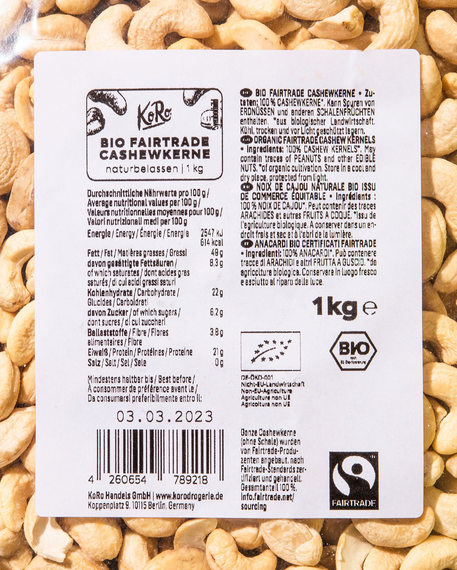 Nahaufnahme eines weißen Produktetiketts von den Bio Fairtrade Cashewkernen von KoRo. Das Etikett zeigt detaillierte Nährwertangaben und Zutaten. Auffällig ist das schwarz-weiße, geschwungene Fairtrade-Logo unten rechts.