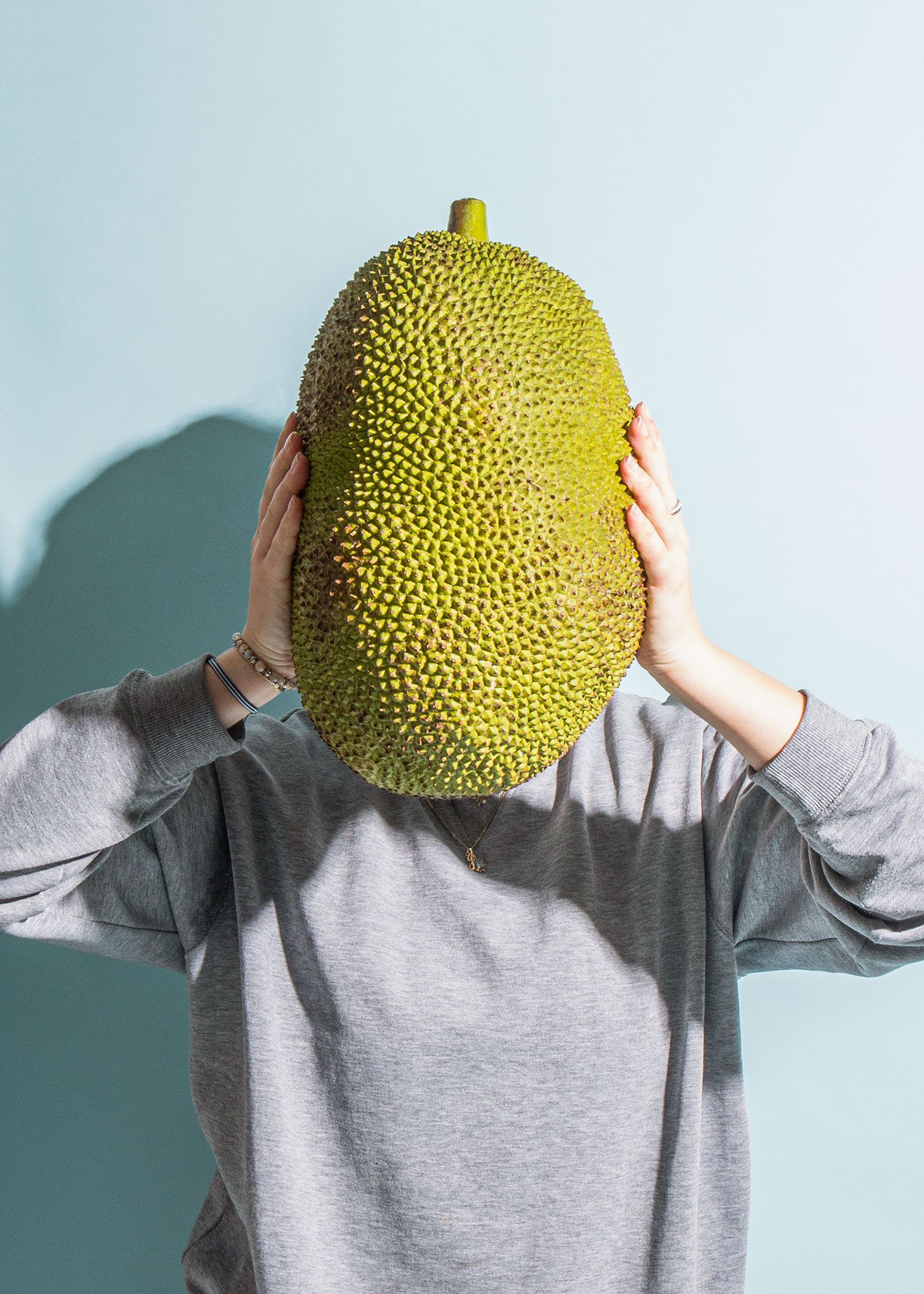 Person hält eine Jackfruit in den Händen.
