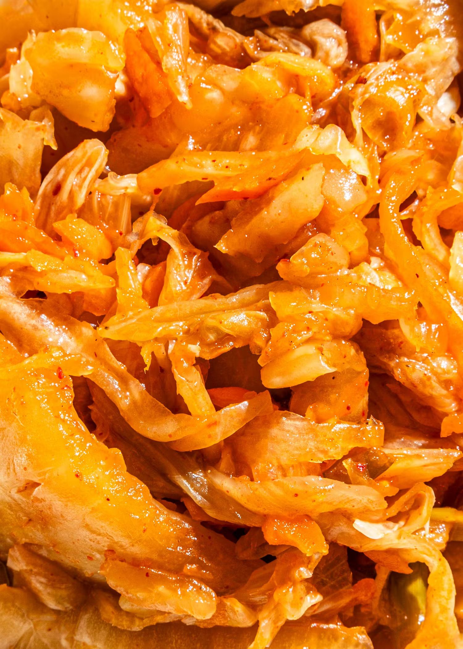 Eine detailreiche Nahaufnahme von würzig fermentiertem Kimchi mit goldgelben Kohlblättern und feinen Chiliflocken.