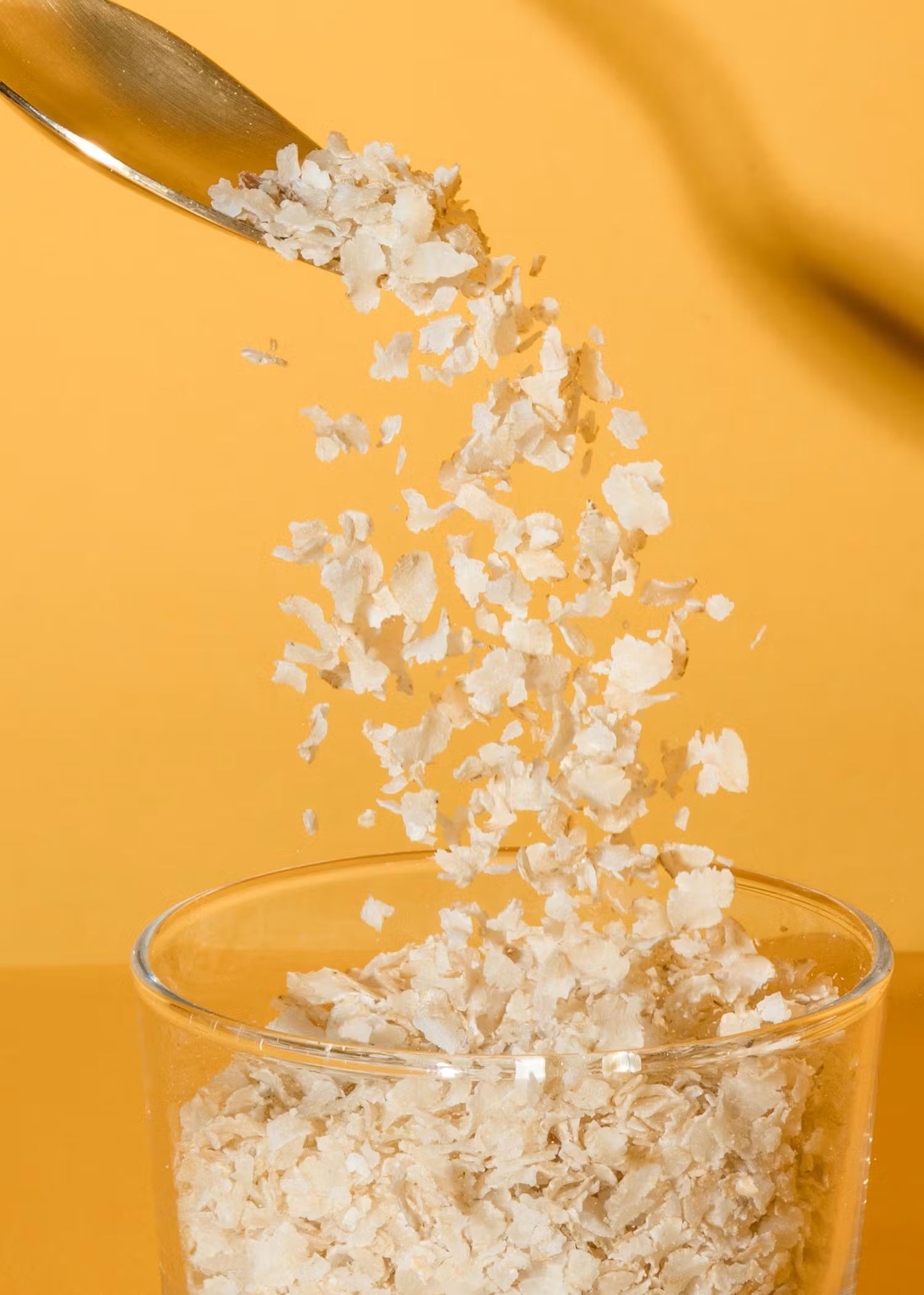 Fiocchi di riso cadono su una ciotola, su sfondo giallo