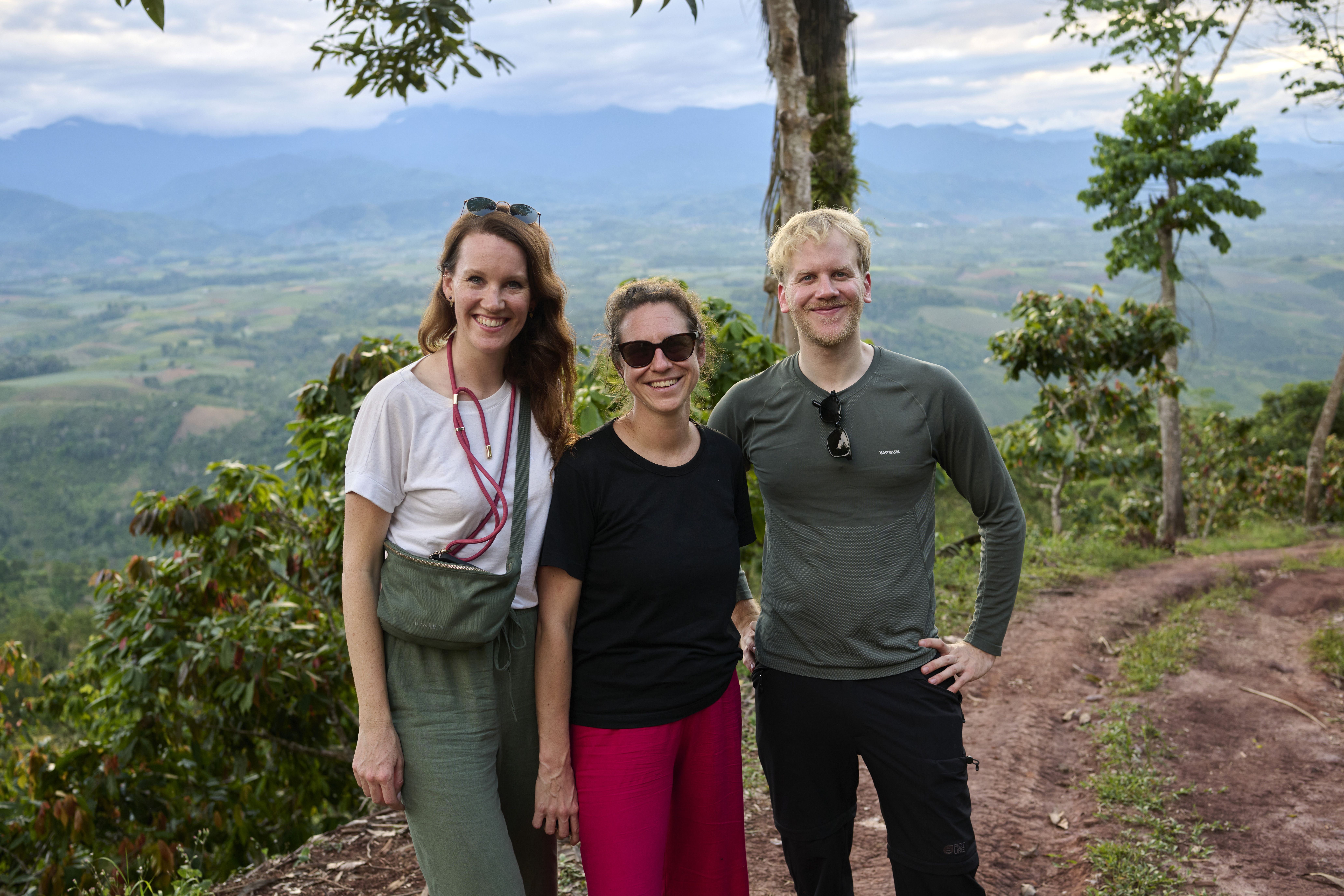 Drei Teammitglieder auf einer Anhöhe vor einer Kakaoplantage in Peru; im Hintergrund erstreckt sich das weite Tal der peruanischen Regenwaldregion während eines Projektbesuchs.