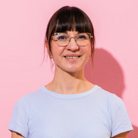 Frau mit Brille und hellem T-Shirt lächelt in die Kamera 