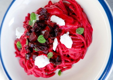 Rote Bete Pasta mit veganem Veta angerichtet in einem tiefen Teller und mit Minzblättern dekoriert