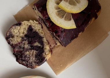 Marmorierter veganer Zitronen-Blaubeer-Kuchen mit Ahorn-Glasur, angeschnitten und auf einem Teller serviert.