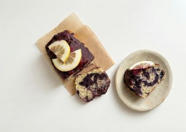 Marmorierter veganer Zitronen-Blaubeer-Kuchen mit Ahorn-Glasur, angeschnitten und auf einem Teller serviert.