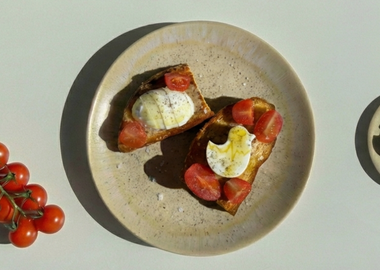 Veganer Feta in Form eines Ostereis und eines Osterküken auf knusprigem Toast, serviert mit Cherrytomaten auf hellem Teller – kreative Idee für Osterbrunch oder Osterfrühstück.
