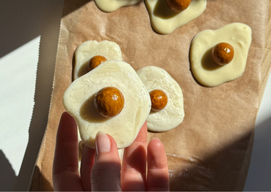 Vegane Spiegeleier aus weißer Schokolade mit gefriergetrockneten Physalis als „Eigelb“ auf Backpapier – kreative Oster-Snack-Idee, handgemacht und dekorativ angerichtet.