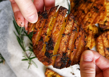 Knusprige Fächerkartoffeln mit Knoblauch und Rosmarin, goldbraun gebacken, serviert mit veganer Trüffel-Mayonnaise – Crispy Garlic Potatoes aus dem Ofen in Nahaufnahme