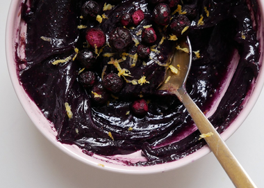 Cremiges Heidelbeer-Zitronen-Mandelmus in einer rosa Schale, garniert mit getrockneten Blaubeeren und Zitronenabrieb.