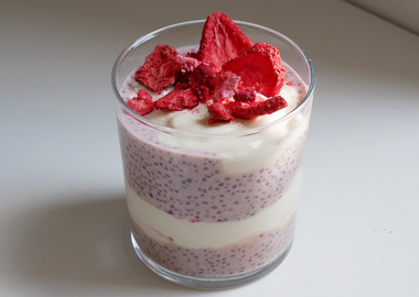 Erdbeer-Chia-Pudding geschichtet mit Joghurt im Glas, garniert mit gefriergetrockneten Erdbeeren.