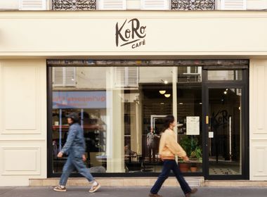 Außenansicht des KoRo Café in Paris mit minimalistischer cremefarbener Fassade, großem Schaufenster und Passanten auf dem Gehweg vor dem Eingang.