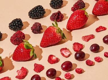 Gefriergetrocknete und frische Beeren wie Erdbeeren, Brombeeren und Cranberries auf hellem Untergrund