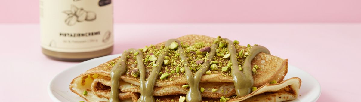 vegane Crêpes auf einem Teller geschichtet mit Pistaziencreme