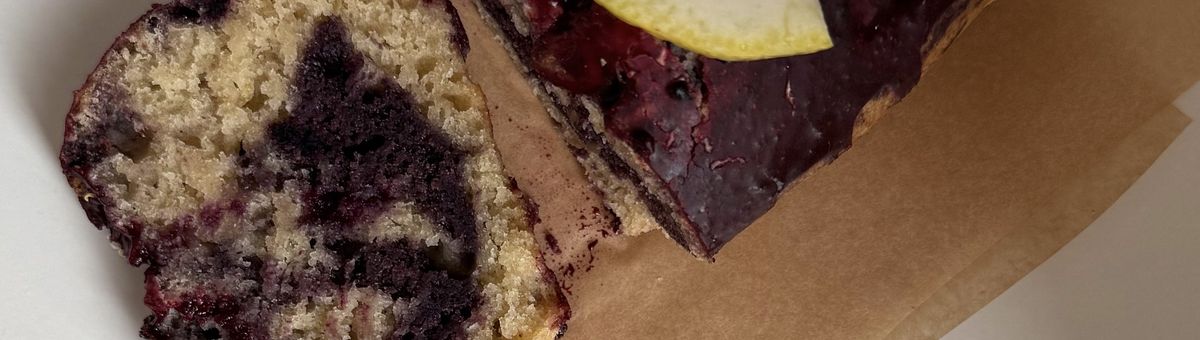 Marmorierter veganer Zitronen-Blaubeer-Kuchen mit Ahorn-Glasur, angeschnitten und auf einem Teller serviert.