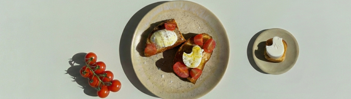 Veganer Feta in Form eines Ostereis und eines Osterküken auf knusprigem Toast, serviert mit Cherrytomaten auf hellem Teller – kreative Idee für Osterbrunch oder Osterfrühstück.