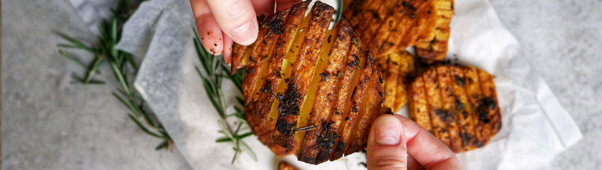Knusprige Fächerkartoffeln mit Knoblauch und Rosmarin, goldbraun gebacken, serviert mit veganer Trüffel-Mayonnaise – Crispy Garlic Potatoes aus dem Ofen in Nahaufnahme
